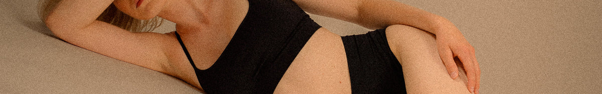 Frau in schwarzem Body mit Fokus auf Bauch, Taille und Beinen als ästhetisches Motiv für Brazilian Lymphdrainage bei migo in Hannover.
