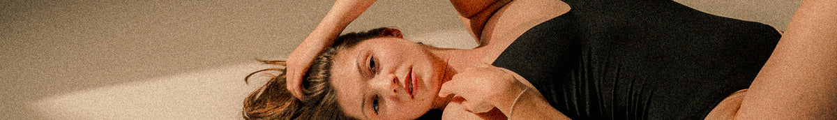Frau in schwarzem Outfit mit ruhiger Pose und natürlichem Beauty-Look als Motiv für Selfcare und Wohlfühlmomente bei migo in Hannover.