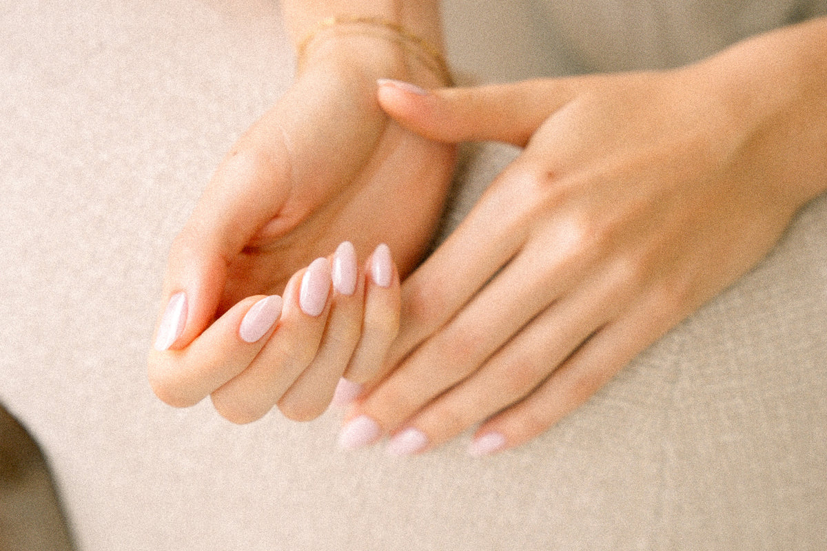 Gepflegte Hände mit präzise geformten, hellrosa glänzenden Nägeln nach einer Russian Manicure bei migo in Hannover.