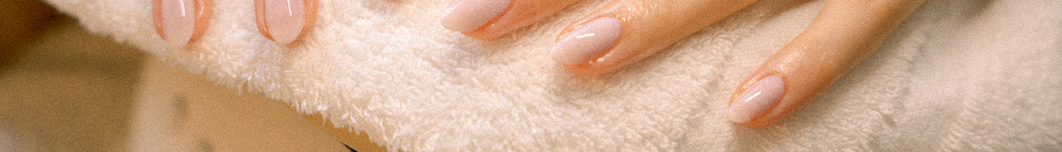 Nahaufnahme gepflegter Hände mit präzise geformten, hellrosa glänzenden Nägeln nach einer Russian Manicure bei migo in Hannover.
